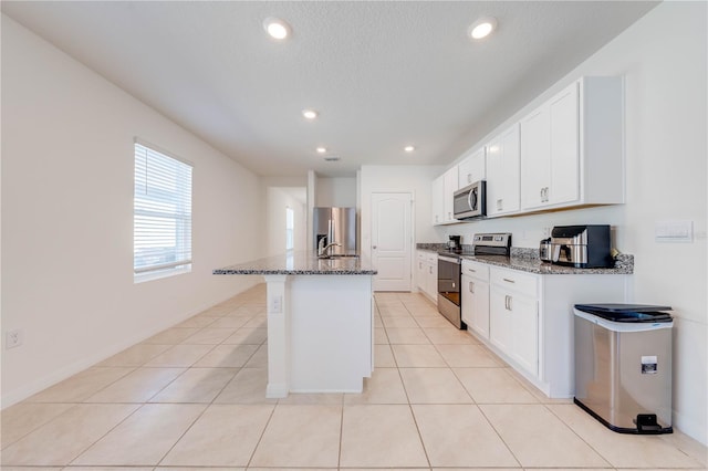2265 Tay Wes Dr, Saint Cloud, FL 34771 - kitchen with stainless steel appliances, a kitchen island with sink, dark stone countertops, and white cabinets