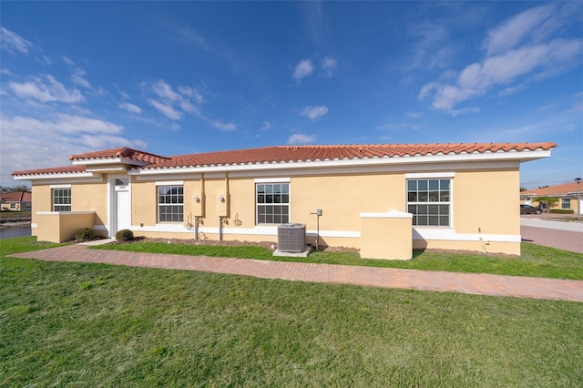 rear view of property featuring central AC unit and a lawn