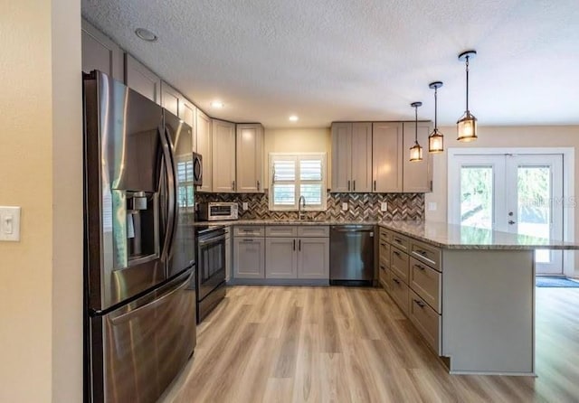 kitchen featuring stone countertops, sink, hanging light fixtures, kitchen peninsula, and stainless steel appliances