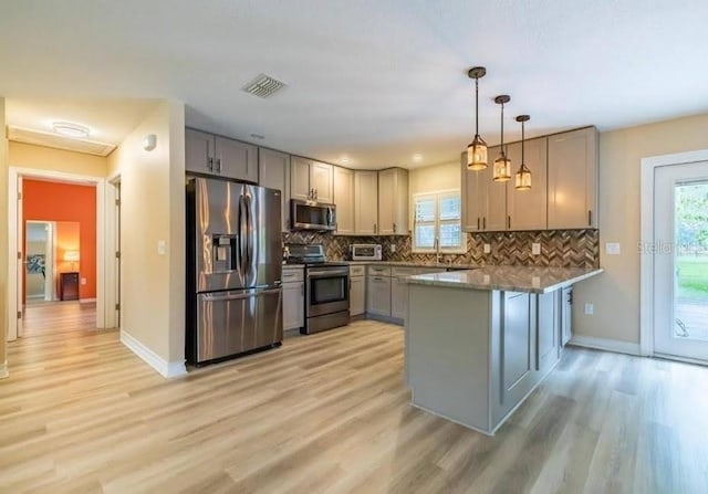 kitchen featuring stainless steel appliances, gray cabinetry, pendant lighting, and kitchen peninsula