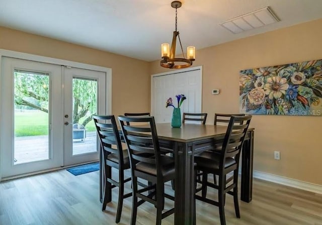 dining area with french doors, light hardwood / wood-style floors, and a notable chandelier