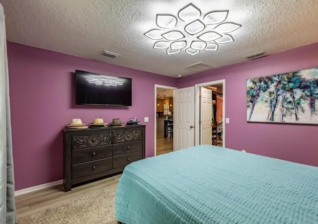 bedroom featuring a textured ceiling and light hardwood / wood-style flooring