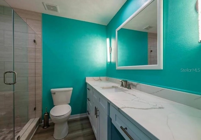 bathroom with vanity, toilet, a shower with shower door, and wood-type flooring
