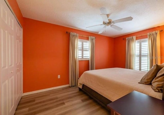 bedroom featuring multiple windows, wood-type flooring, a closet, and a textured ceiling