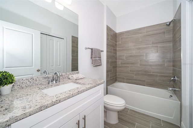 full bathroom with tiled shower / bath, vanity, and toilet