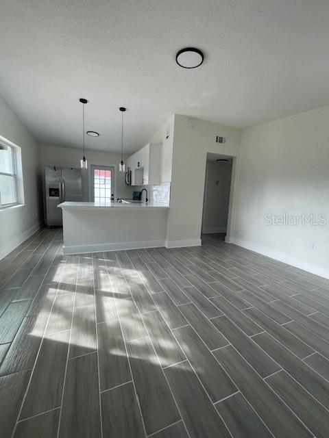 kitchen featuring pendant lighting, kitchen peninsula, white cabinets, and appliances with stainless steel finishes