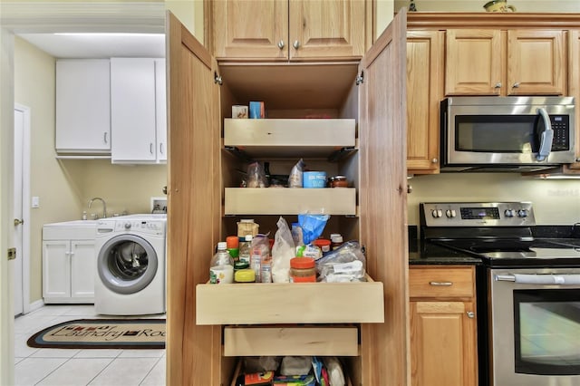 laundry area featuring sink, light tile patterned floors, washer / dryer, and cabinets