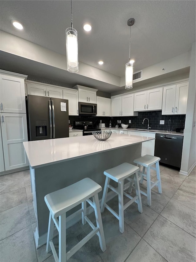 kitchen with white cabinets, black appliances, light countertops, and hanging light fixtures