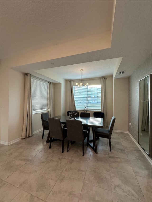 dining room with visible vents, a notable chandelier, a textured ceiling, and baseboards