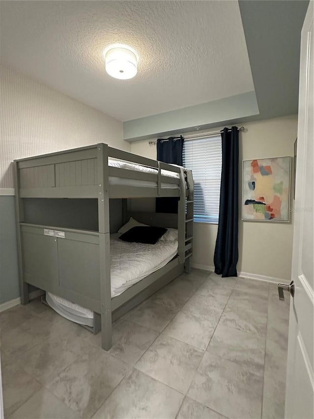 bedroom featuring marble finish floor, baseboards, and a textured ceiling