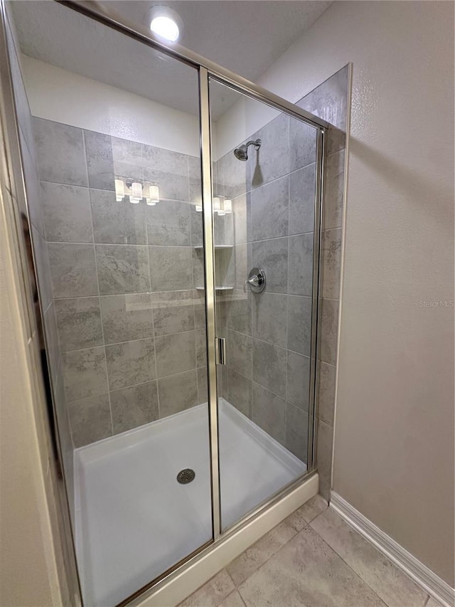 full bath featuring a stall shower, baseboards, and tile patterned floors