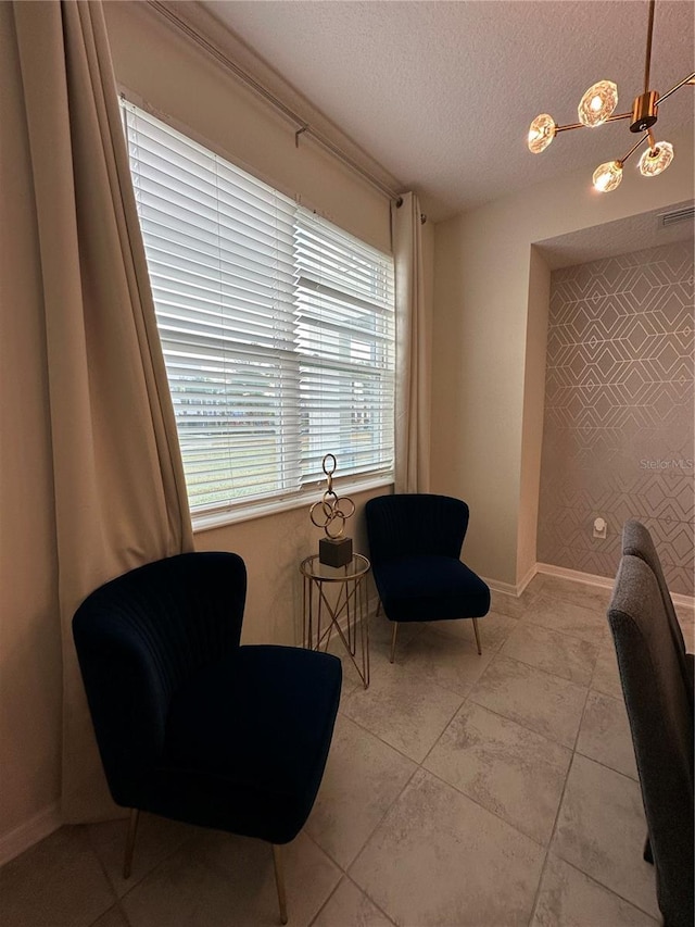 living area featuring a textured ceiling, light tile patterned floors, an accent wall, visible vents, and baseboards