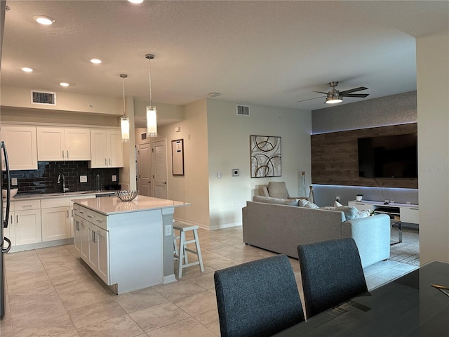 kitchen with light countertops, hanging light fixtures, visible vents, and white cabinets