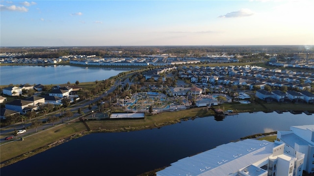 aerial view at dusk with a water view and a residential view