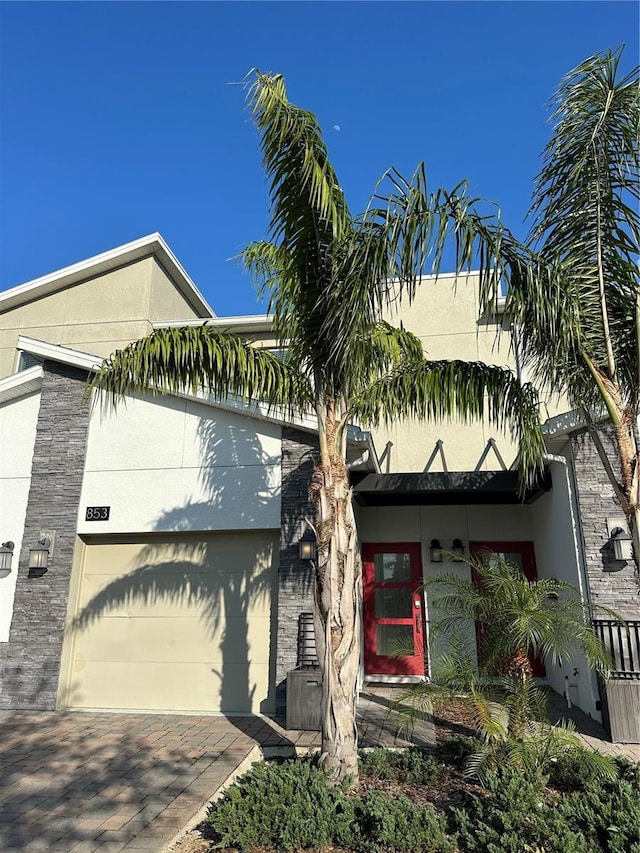 view of front of home with an attached garage, decorative driveway, and stucco siding