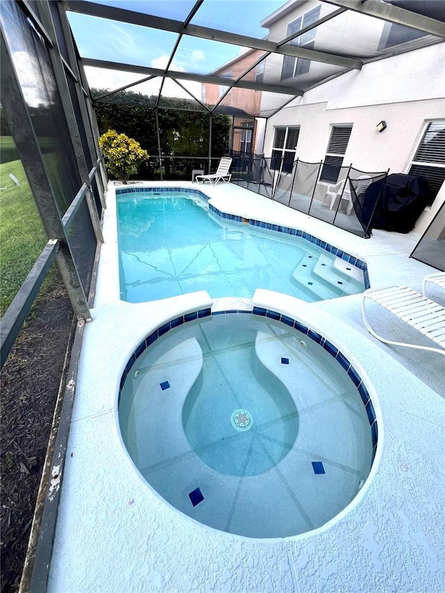 view of pool with a lanai and an in ground hot tub