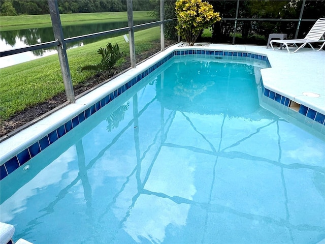 view of swimming pool with a water view, a lawn, and a lanai