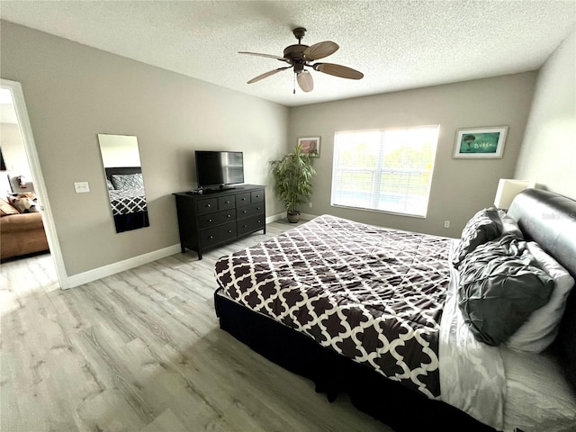 bedroom with a textured ceiling, ceiling fan, and light wood-type flooring