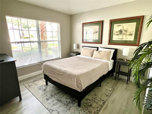 bedroom with multiple windows and light hardwood / wood-style floors