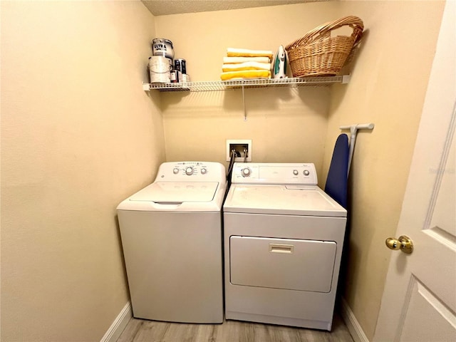 clothes washing area with washer and dryer and light wood-type flooring