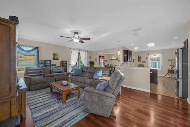 living room featuring sink, dark wood-type flooring, and ceiling fan with notable chandelier