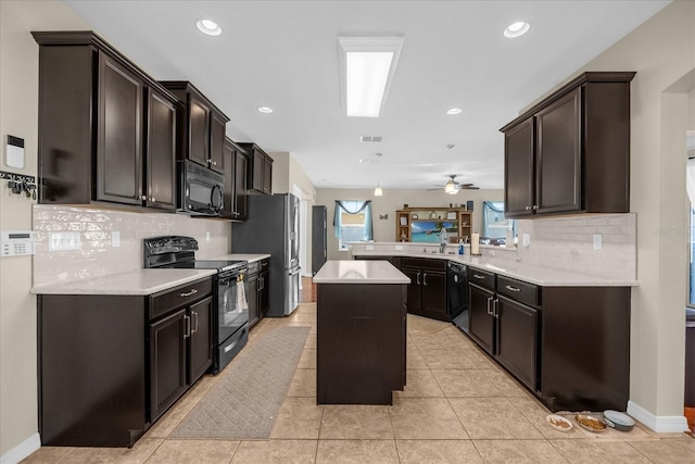 kitchen with a kitchen island, tasteful backsplash, black appliances, light tile patterned floors, and kitchen peninsula