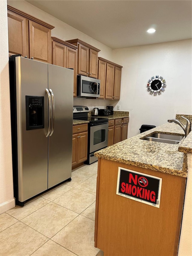 kitchen with appliances with stainless steel finishes, light stone countertops, sink, and light tile patterned floors