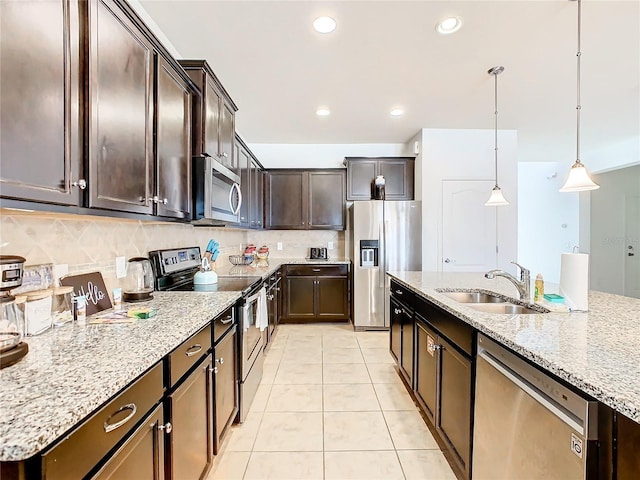 kitchen featuring sink, decorative light fixtures, dark brown cabinets, light tile patterned floors, and appliances with stainless steel finishes