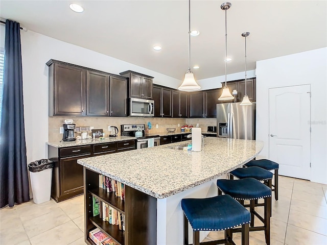 kitchen with appliances with stainless steel finishes, a center island, pendant lighting, and dark brown cabinetry