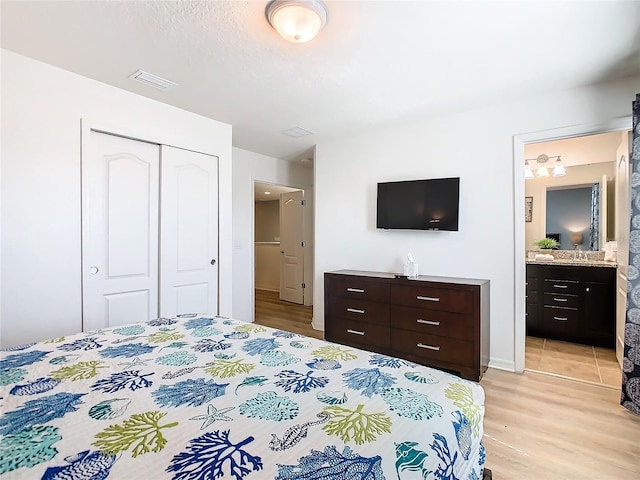 bedroom featuring ensuite bath, a closet, and light wood-type flooring