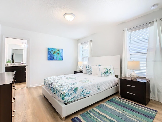 bedroom featuring ensuite bathroom and light hardwood / wood-style flooring