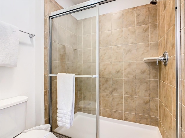 bathroom featuring toilet and a shower with shower door