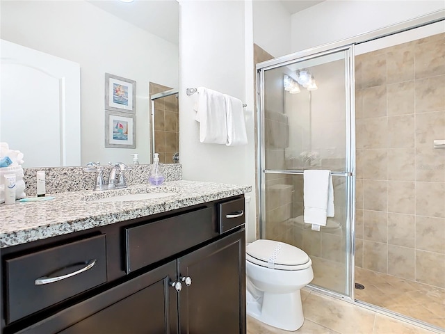 bathroom featuring walk in shower, vanity, toilet, and tile patterned flooring