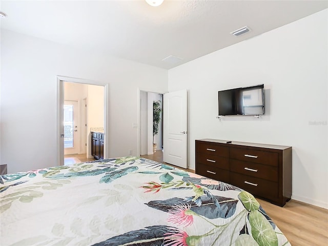 bedroom featuring connected bathroom and light hardwood / wood-style flooring