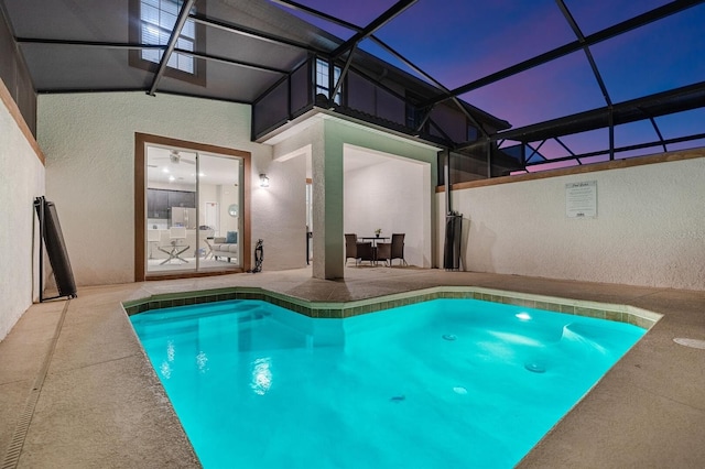 pool at dusk with a patio and a lanai