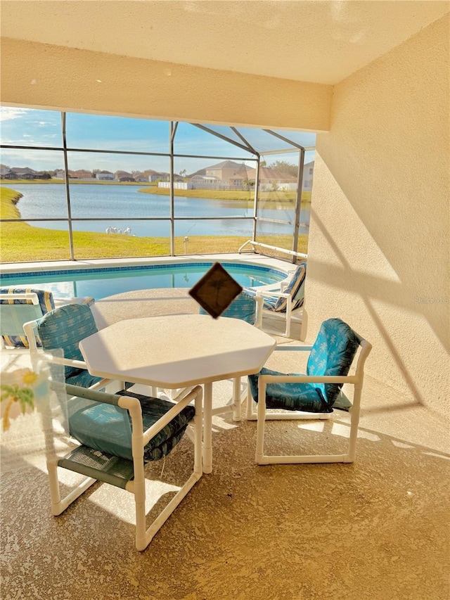 view of patio / terrace featuring a pool with hot tub, glass enclosure, and a water view