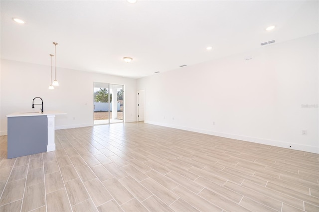 unfurnished living room with sink and light hardwood / wood-style flooring