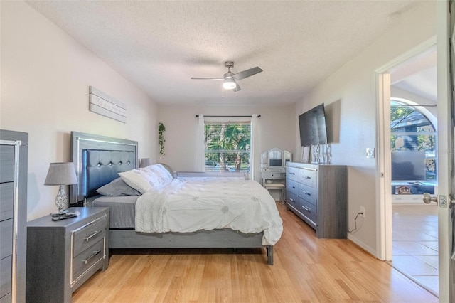 bedroom featuring ceiling fan, a textured ceiling, and light wood-type flooring