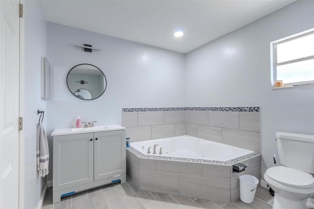 bathroom with vanity, tiled bath, and toilet