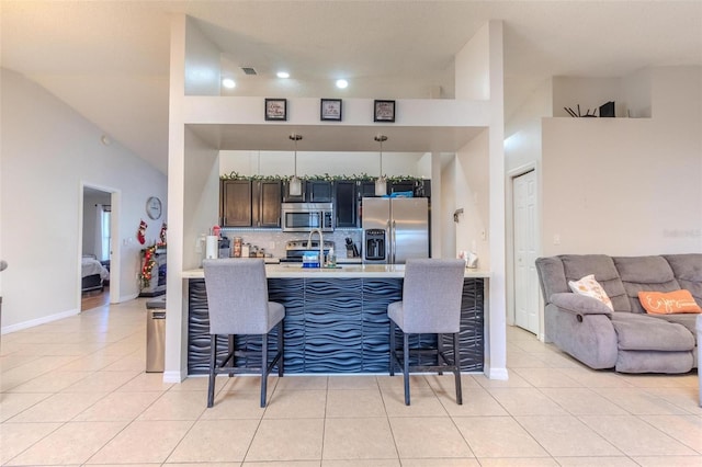 kitchen featuring hanging light fixtures, stainless steel appliances, a breakfast bar, and light tile patterned flooring