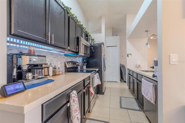 kitchen with lofted ceiling, appliances with stainless steel finishes, backsplash, light tile patterned flooring, and decorative light fixtures