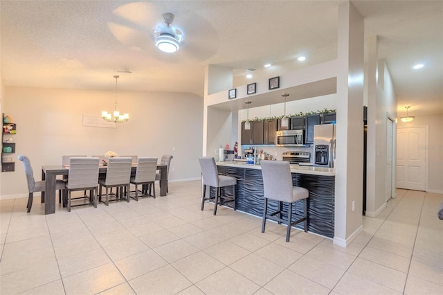 kitchen featuring appliances with stainless steel finishes, a kitchen breakfast bar, light tile patterned floors, a notable chandelier, and kitchen peninsula