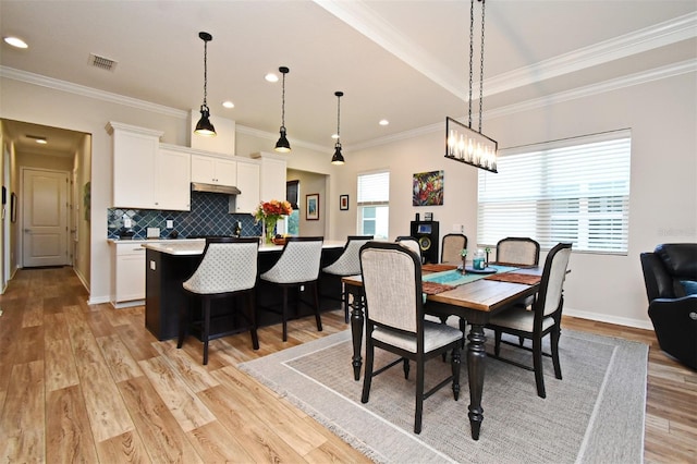 dining space featuring crown molding and light hardwood / wood-style flooring