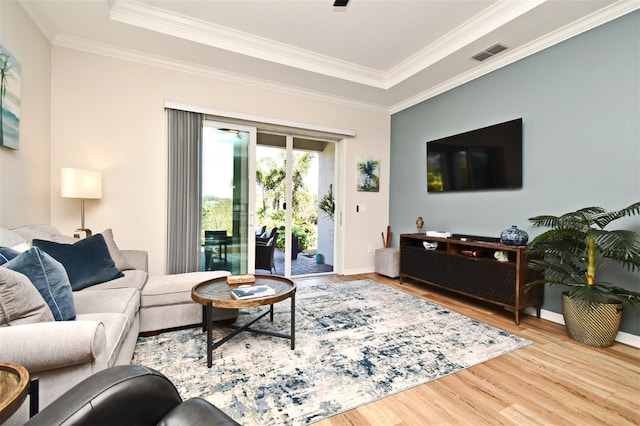 living room with crown molding, hardwood / wood-style flooring, and a tray ceiling