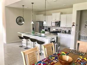 kitchen featuring appliances with stainless steel finishes, pendant lighting, white cabinets, and decorative backsplash