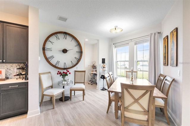 dining room featuring light hardwood / wood-style flooring and a textured ceiling