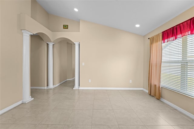 empty room featuring lofted ceiling, decorative columns, and light tile patterned floors