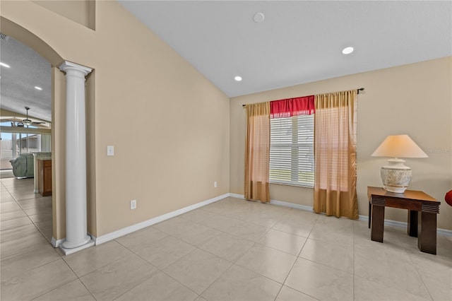 empty room featuring decorative columns, lofted ceiling, light tile patterned floors, and ceiling fan