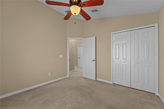 unfurnished bedroom with ceiling fan, a closet, vaulted ceiling, and light carpet