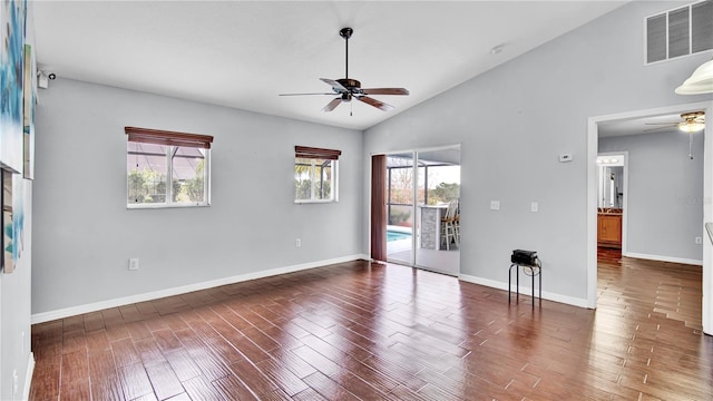 spare room featuring vaulted ceiling, a healthy amount of sunlight, dark wood-type flooring, and ceiling fan